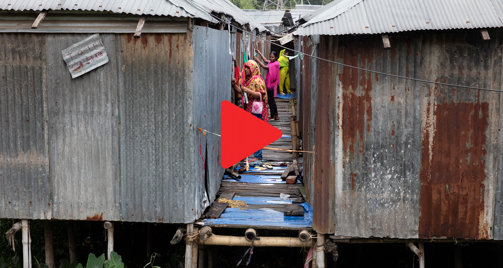 Bild på slum i Bangladesh med en röd play-knapp
