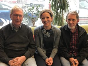 Tre podcastgäster sitter i en soffa, i bakgrunden är ett fönster ut mot gatan där bilar står parkerade