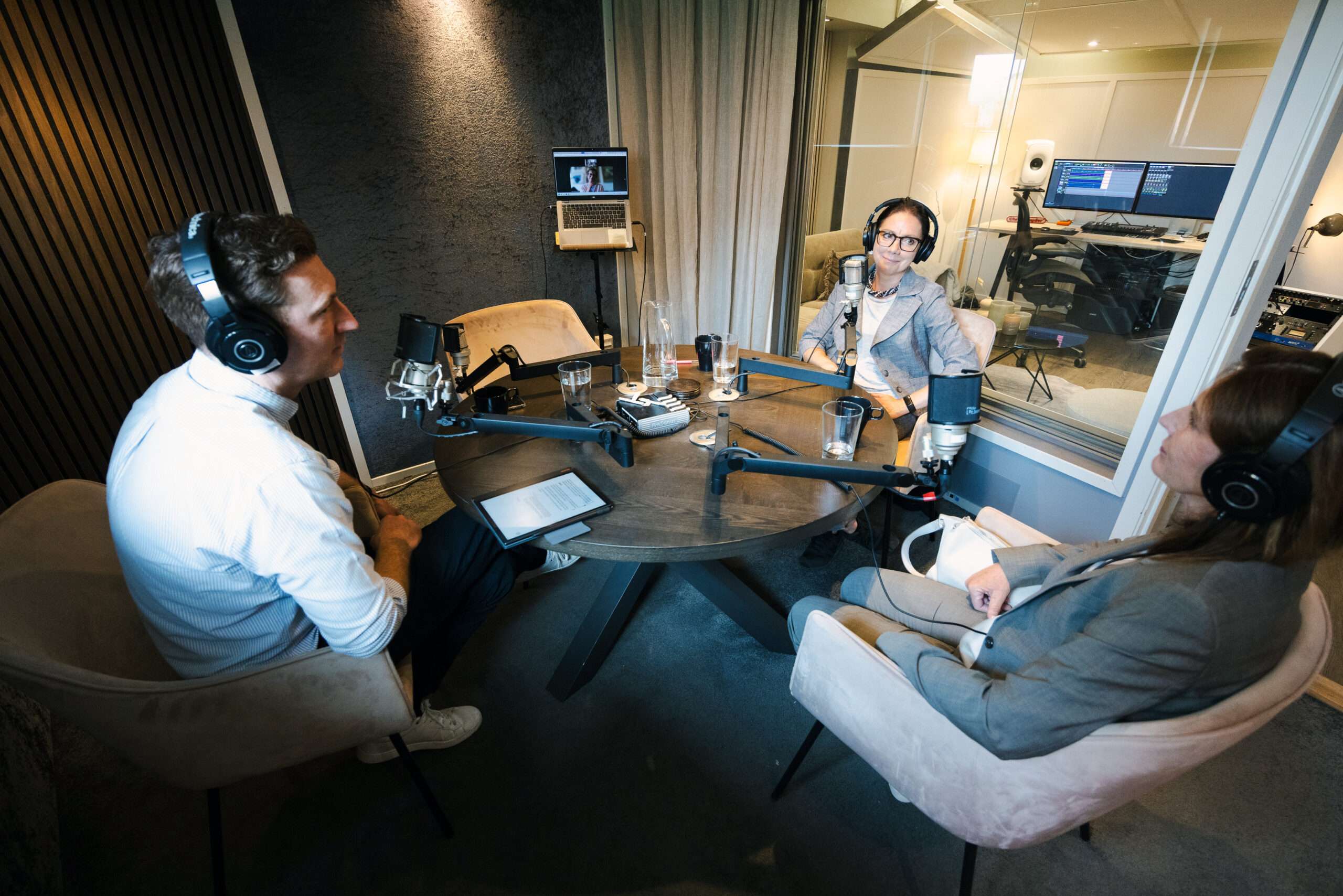 En man, två kvinnor och en dator med en kvinna i en poddstudion