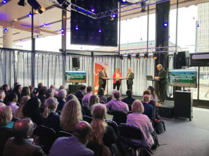 Paneldiskussion med tre män och en kvinna framför publik