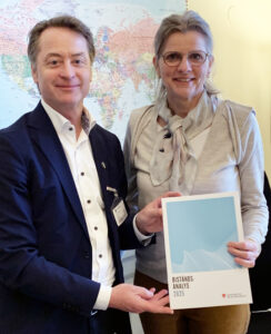 En man och en kvinna håller i en broschyr med titeln Biståndsanalys 2025