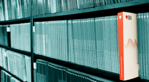 En bokhylla med många grå rapporter, där en sticker ut i rött med EBA-logga