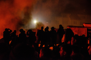 Dark red picture with black silhouettes of people fighting