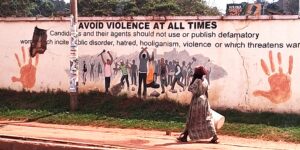 Woman passing a wall with the text: Avoid violence at all times