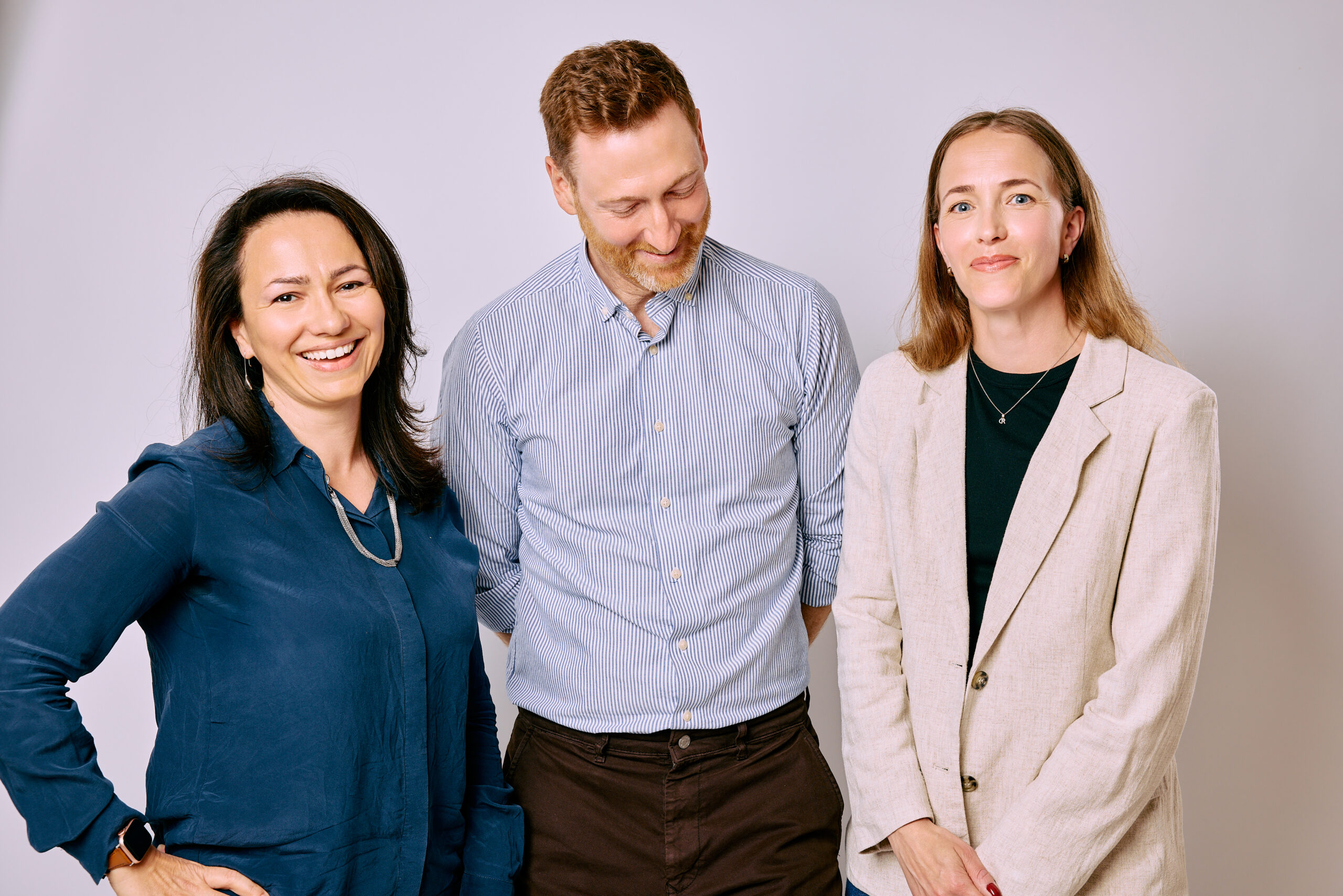 Två kvinnor och en man mot vit bakgund
