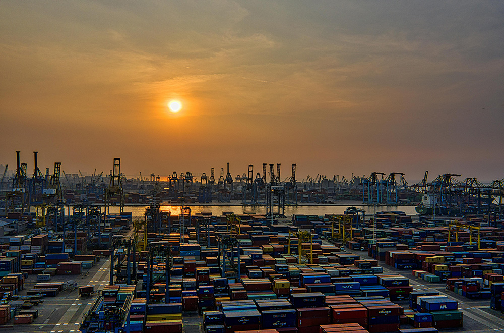 Gul sol över hamnområde med containrar